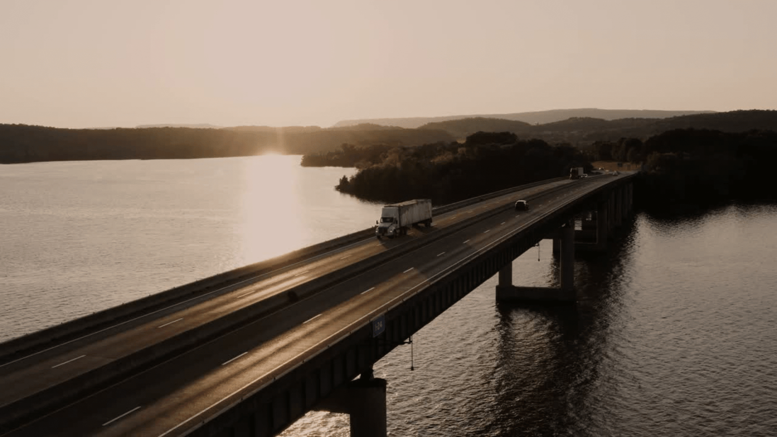 Tractor trailer crossing a bridge at sunset