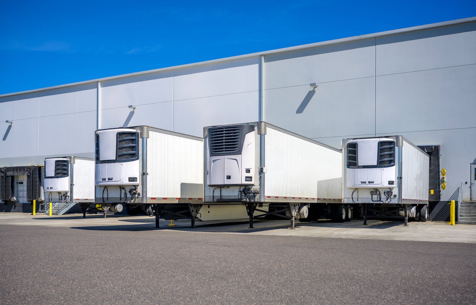 Refrigerated trailers backed into loading dock doors at a distribution warehouse