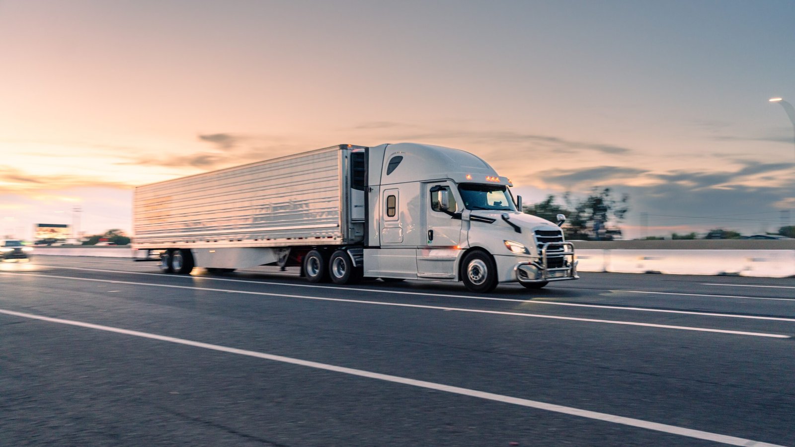 Refrigerated tractor trailer running on the highway at dusk